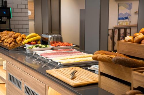 a buffet with bread and other food on a counter at Holiday Inn Express - Rosenheim by IHG in Rosenheim