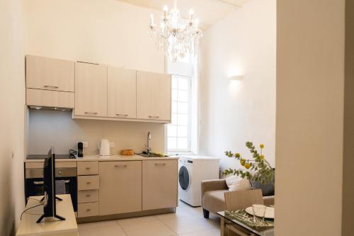 a kitchen with white cabinets and a living room at Unique 1 bedroom in hearth of old city Valetta in Valletta