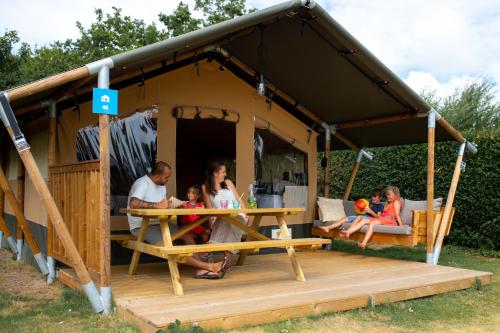 a family sitting at a table in a tent at RCN Vakantiepark Toppershoedje in Ouddorp