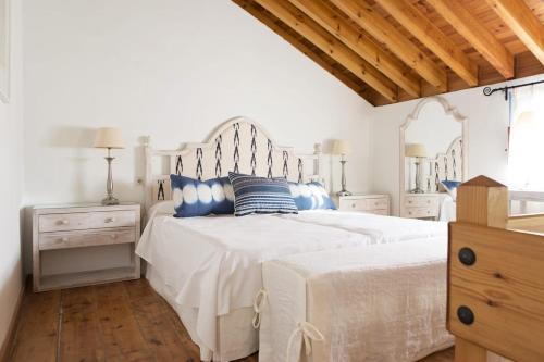 a bedroom with a white bed with blue pillows at Hotel Cortijo del Arte - Caminito del Rey in Pizarra