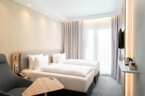 a hotel room with a white bed and a couch at Holiday Inn Express - Rosenheim by IHG in Rosenheim