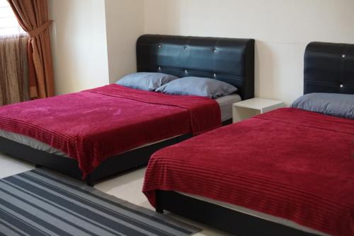 um quarto com 2 camas e lençóis vermelhos em Warisan Indah Homestay KLIA 2 em Kampong Melot