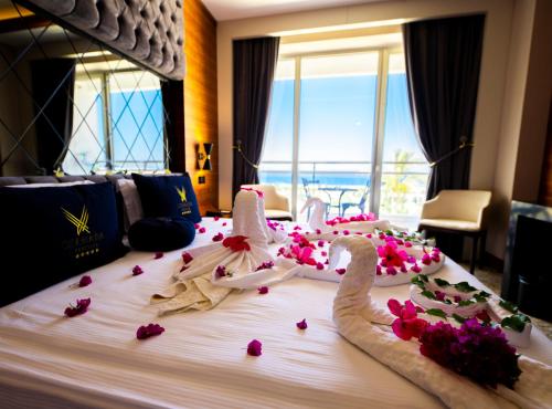 キレニアにあるChamada Prestige Hotel and Casinoのホテル内のベッドにウェディングドレスと花を飾ります。