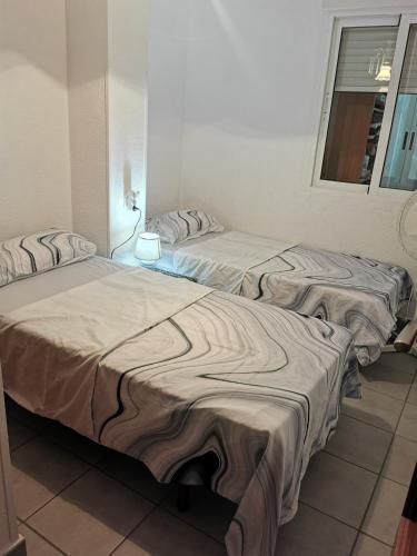 two beds sitting in a room with a window at San Pedro del Pinatar Lo Pagan, Calle Gibraltar 19 - app 2A in San Pedro del Pinatar