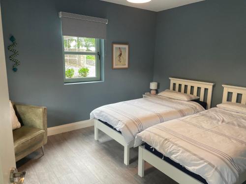 1 dormitorio con 2 camas, silla y ventana en The Potters Lodge en Carrick on Shannon