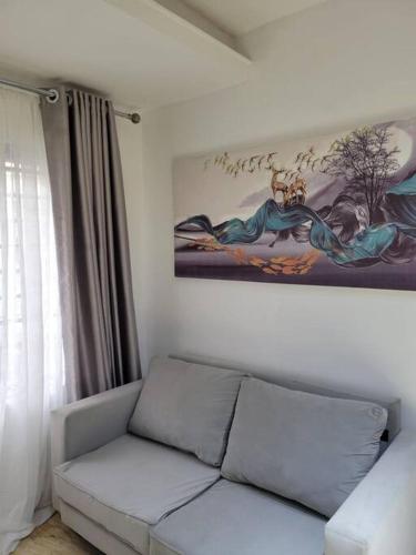 a living room with a couch and a painting on the wall at Lovely 2-Bedroom rental unit with amenities. in Abuja