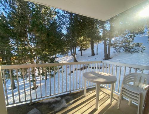 a balcony with a table and chairs and snow on the ground at Superbe appartement vue sur la forêt in Les Angles