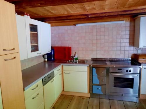 een keuken met witte kasten en een roestvrijstalen kachel bij Ferienwohnung Oberpursteinhof in Campo Tures