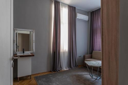 a bathroom with a sink and a mirror and a chair at Luxury Apart Vitosha Boulevard in Sofia