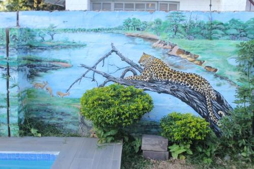 a painting of a leopard sitting on a tree branch at Universe GuestHouse in Kasane