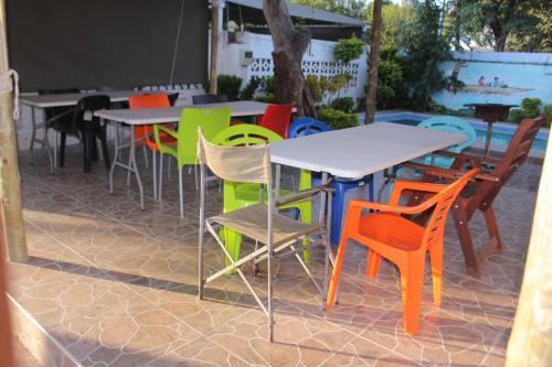 um grupo de mesas e cadeiras coloridas num pátio em Universe GuestHouse em Kasane