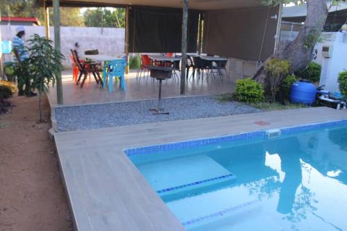 a swimming pool in a yard with a table and chairs at Universe GuestHouse in Kasane