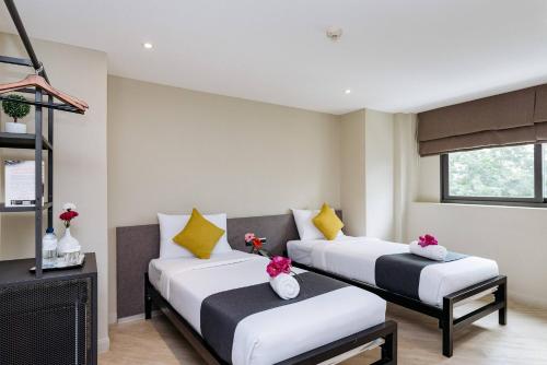 2 Betten in einem Zimmer mit weißen und gelben Kissen in der Unterkunft Lucky House Khaosan in Bangkok