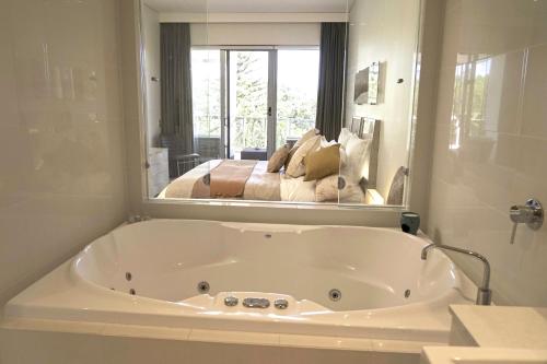 y baño con bañera blanca y espejo. en Peppers Balé Luxury Beach Accommodation Kingscliff - privately let, en Kingscliff
