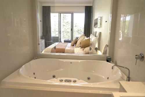 a white bath tub in a bathroom with a mirror at Peppers Balé Luxury Beach Accommodation Kingscliff - privately let in Kingscliff