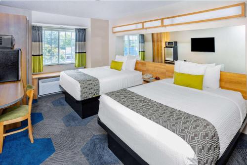 a hotel room with two beds and a flat screen tv at Microtel Inn & Suites by Wyndham Johnstown in Johnstown