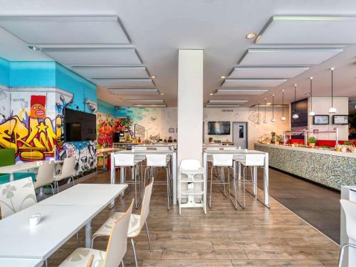 a restaurant with white tables and chairs and a kitchen at ibis Styles Hotel Berlin Mitte in Berlin