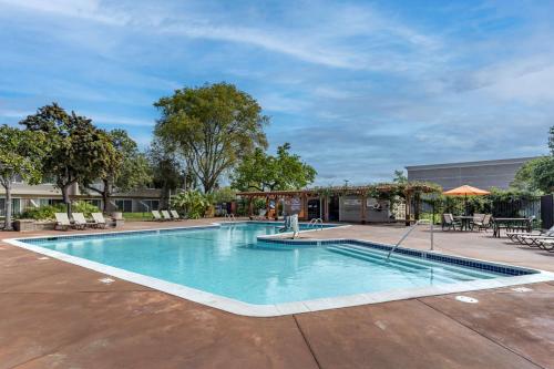 a swimming pool in a courtyard with chairs and tables at Best Western Plus Garden Court Inn in Fremont