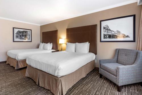 a hotel room with two beds and a chair at Best Western Plus Garden Court Inn in Fremont