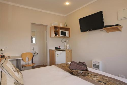 a bedroom with a bed with a flat screen tv on the wall at Big Five Motel in Palmerston North