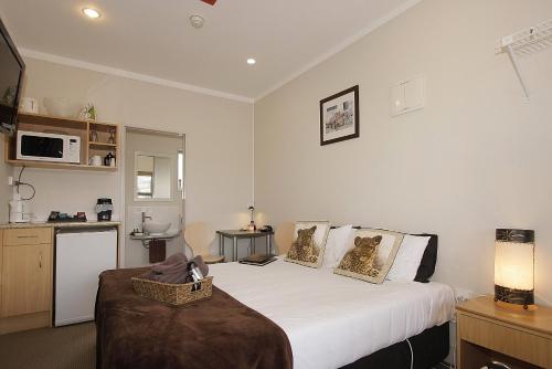 a bedroom with a large white bed and a kitchen at Big Five Motel in Palmerston North
