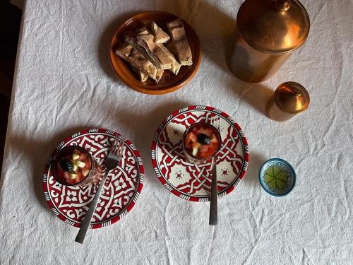 three plates on a table with a bowl of food at Berber Nomad Kasbah in Nkob