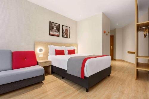 a hotel room with a bed and a couch at Ramada by Wyndham Madrid Tres Cantos in Tres Cantos