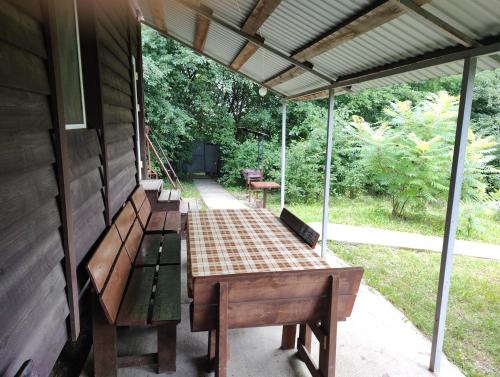 eine abgeschirmte Veranda mit Bänken an der Seite eines Hauses in der Unterkunft Barbecue House in Winnyzja