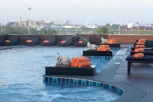 a pool with some animals on orange pillows in the water at Dang Derm In The Park Khaosan in Bangkok