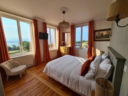 een slaapkamer met oranje gordijnen en een bed met een stoel bij La Terrasse de l'Estuaire - Honfleur in Honfleur