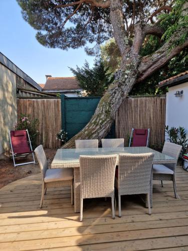 uma mesa e cadeiras num deque com uma árvore em Villa Bagatelle à 300m de la plage centrale, 3 chambres em Arcachon