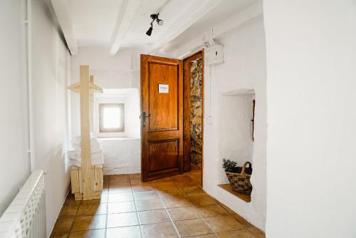 a hallway with a wooden door and a cross on the wall at Cases Altes de Posada in Navés