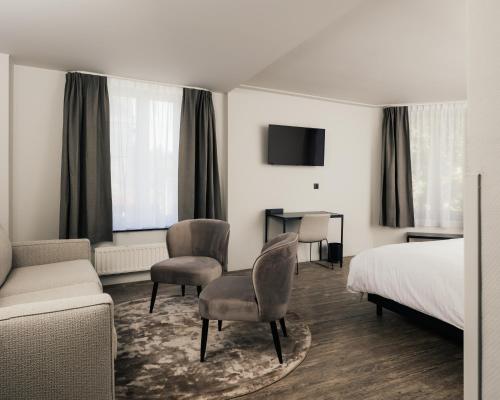 um quarto de hotel com uma cama, um sofá e cadeiras em Hotel Au lit des ours em Han-sur-Lesse