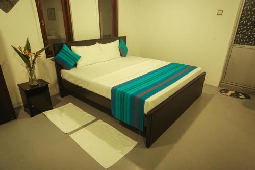 a small bedroom with a bed with blue and white sheets at Navis villa in Galle