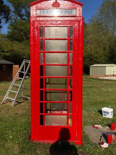 a red phone booth sitting in the grass at South Lodge House in Dormans Land