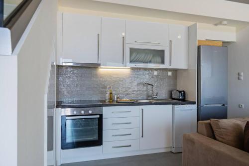 a kitchen with white cabinets and a stove top oven at Sofia Suite, a seafront hideaway ! in Panormos Rethymno