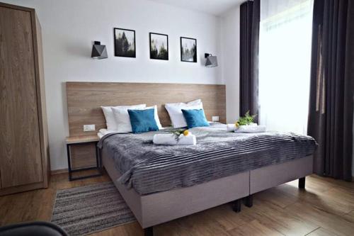 a bedroom with a large bed with blue pillows at Willa Domiwera in Polańczyk