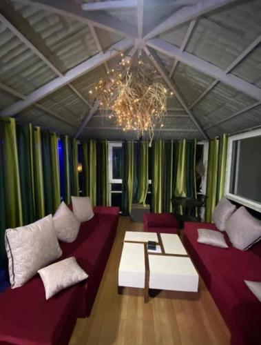 a living room with red couches and a chandelier at Forrest Homestay Villa in Bhor