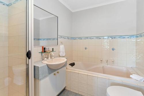 a bathroom with a sink and a tub and a toilet at Stay Inn in Apollo Bay