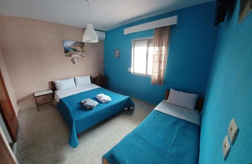 Habitación azul con 2 camas y ventana en APARTMENTS HARIS, en Olympiakí Aktí