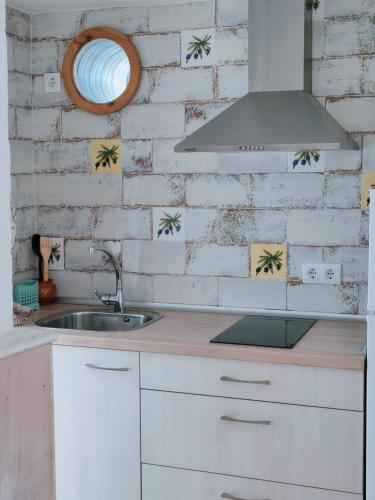 a kitchen with a sink and a brick wall at Casa Leonor Vejer in Vejer de la Frontera