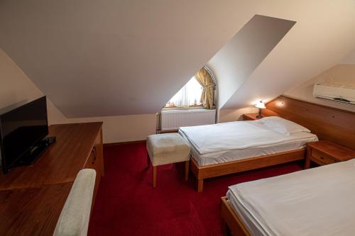 a attic room with two beds and a television at Hotel Vila Lago in Palić