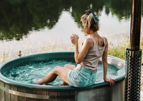 a woman sitting in a hot tub with a cup of coffee at Promowa17 in Rogóźno