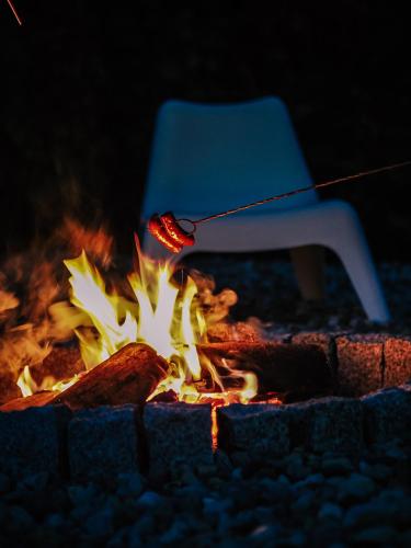 a fire pit with a hot dog and a chair at Promowa17 in Rogóźno