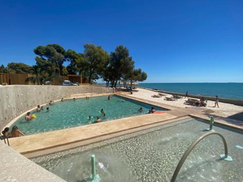 uma piscina numa praia com pessoas na água em Alfacs Village em Les Cases d'Alcanar