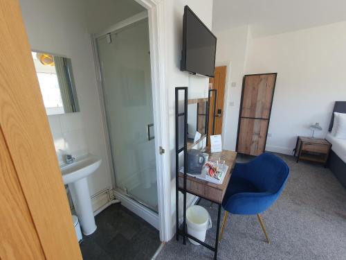 a room with a bathroom with a sink and a blue chair at North Cambridge Guesthouse by Payman Club in Cambridge