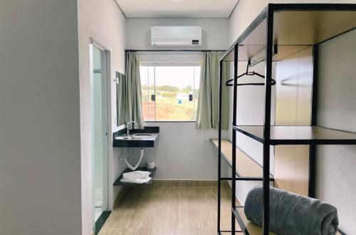 a room with a bunk bed and a sink and a mirror at Brisa do Lago Pousada in Capitólio