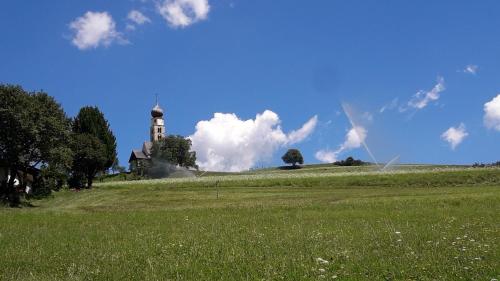 a building on top of a hill with a green field at Apartment Bellevue Seis in Siusi
