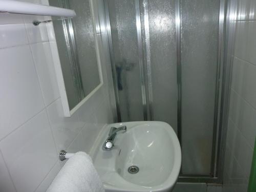 baño blanco con ducha y lavamanos en Pensión Fonda Vilalta, en Ribes de Freser