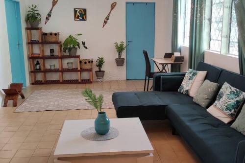 a living room with a blue couch and a table at Maison dans le quartier historique de St Laurent Résidence Colibri in Saint-Laurent du Maroni